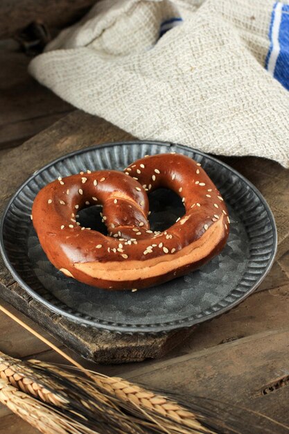 Bretzel de lessive salé allemand traditionnel avec du sel sur une serviette de cuisine en coton à carreaux sur une table en bois de planche blanche. Bannière d'affiche pour le menu du café-boulangerie. Carte Oktoberfest.