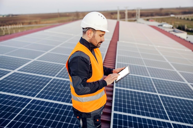 Un bricoleur défilant sur une tablette et vérifiant les panneaux sur le toit