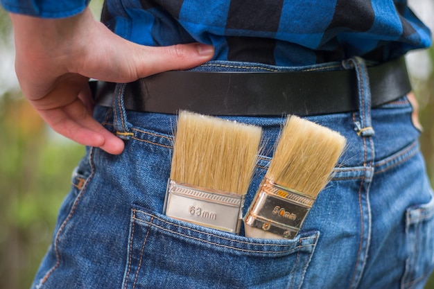 Bricoleur à la maison Vue arrière d'un jeune homme avec des pinceaux dans sa poche