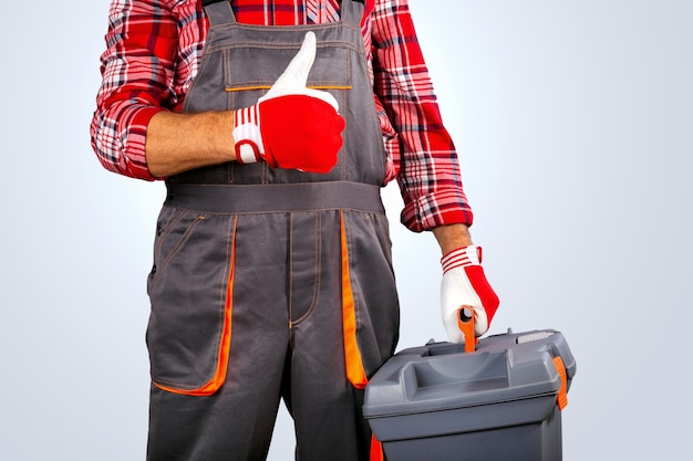 Bricoleur avec le pouce de la boîte à outils sur fond gris.