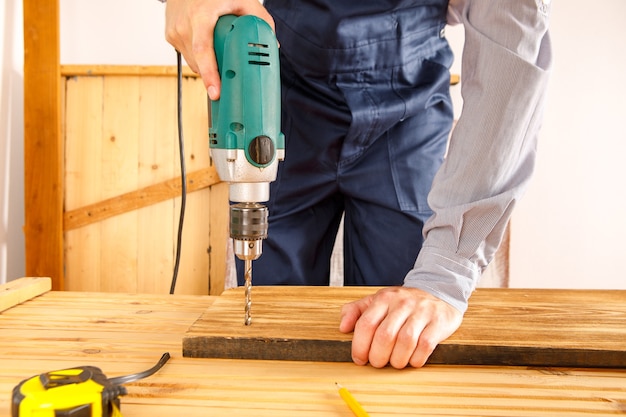 Le bricoleur en uniforme bleu travaille avec un tournevis automatique électrique. Conception de rénovation de maison.