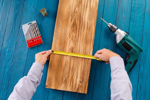 Le bricoleur en uniforme bleu travaille avec un tournevis automatique électrique. Conception de rénovation de maison.