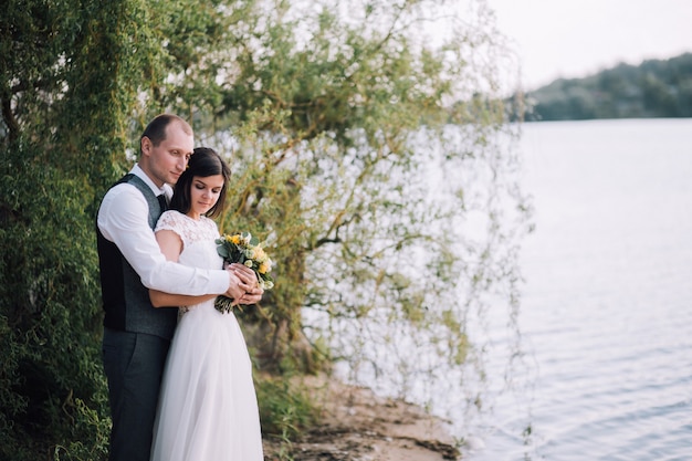 Bride and Groom hugging le jour du mariage, heureux jeune couple s'embrassant dans le parc dans la nature, la Saint-Valentin