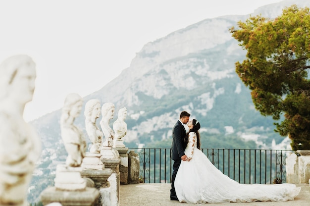 Bride et le marié s&#39;embrassent debout sur le vieux balcon de pierre