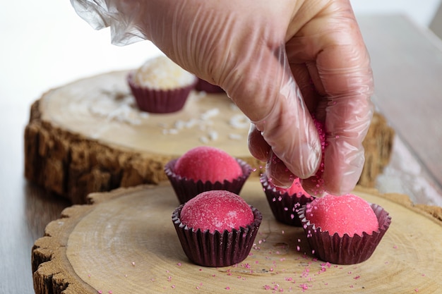 Brigadeiros aux fraises (Bicho de Pe) sur des plats de tronc d'arbre. Confiseur mettant du sucre cristal rose.