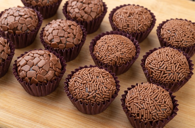 Photo brigadeiros brésiliens typiques, diverses saveurs sur planche de bois.