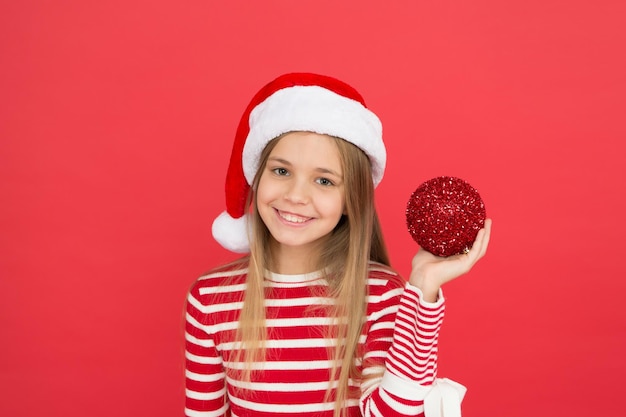 Brillance et paillettes. Chapeau de costume de père Noël pour enfant. Visage souriant heureux. Beau détail. Notion de positivité. Humeur joyeuse. Fête de Noël. Vacances d'hiver. Ambiance ludique. Idées de fête de Noël.