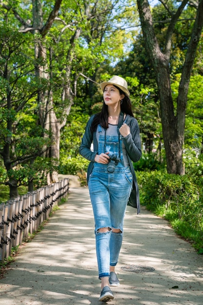 brillante jeune belle fille marchant sur le côté dans un jardin japonais plein de buissons et d'arbres