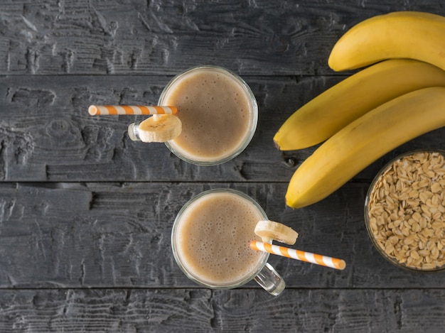 Un brin de bananes, smoothies et flocons d'avoine sur une table en bois