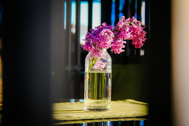 Un brin de lilas dans un bocal transparent est sur la table