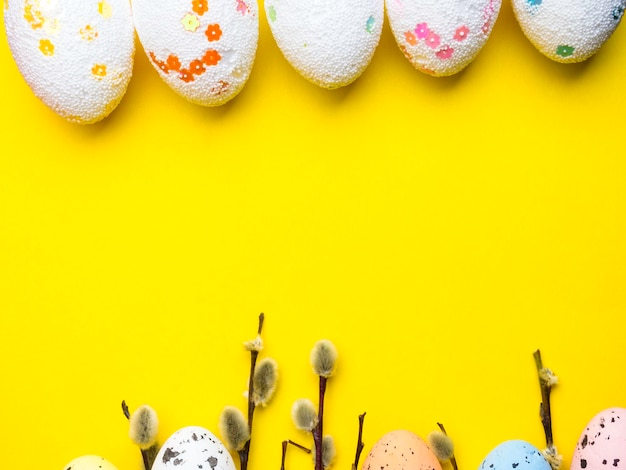 Brindilles de Pussywillow avec des oeufs de Pâques isolés sur le concept jaune de printemps et de Pâques