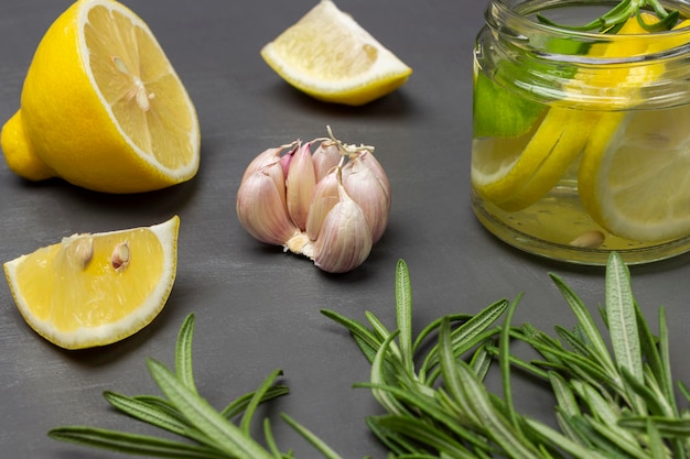 Brins de romarin ail et citron sur la table Boisson au citron dans un bocal en verre