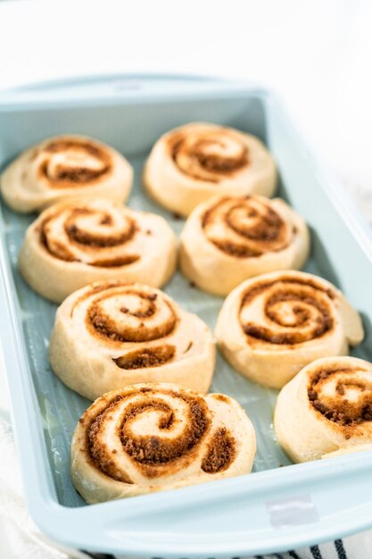 Brioches à la cannelle non cuites dans un plat allant au four bleu