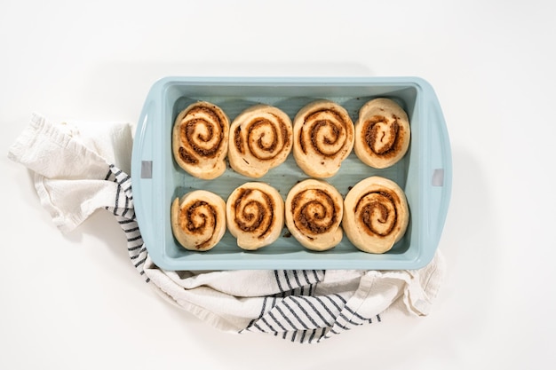 Brioches à la cannelle non cuites dans un plat allant au four bleu