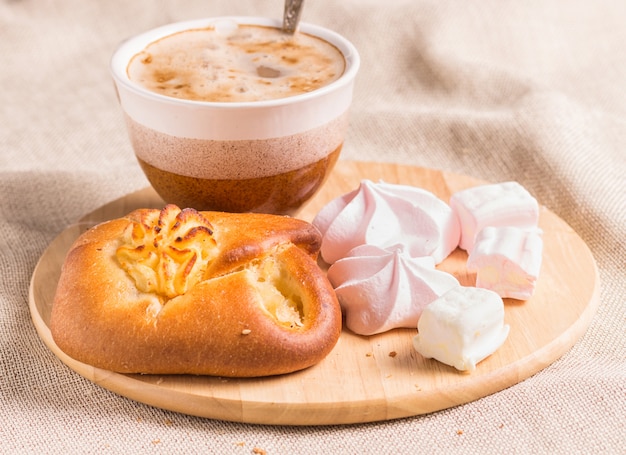 Brioches, meringues et tasse à café sur une planche de bois