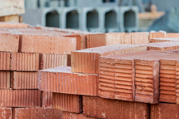 Briques en céramique rouges empilées sur un chantier de construction. Matériaux de construction. Brique rouge pour construire une maison.