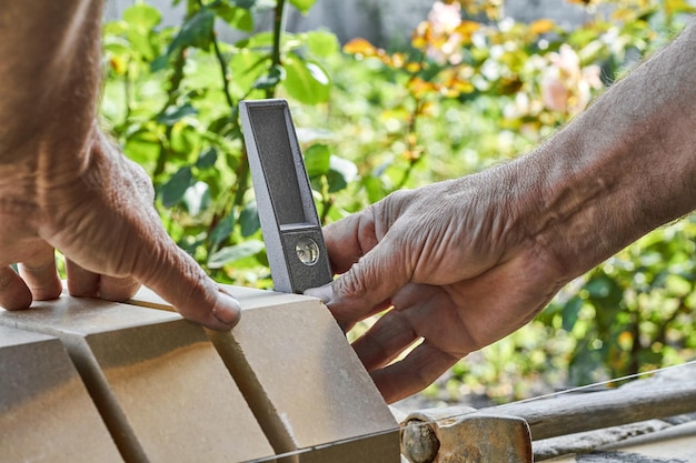 Briques de nivellement de maçon sur la nouvelle clôture à partir de briques de parement en utilisant le niveau du bâtiment