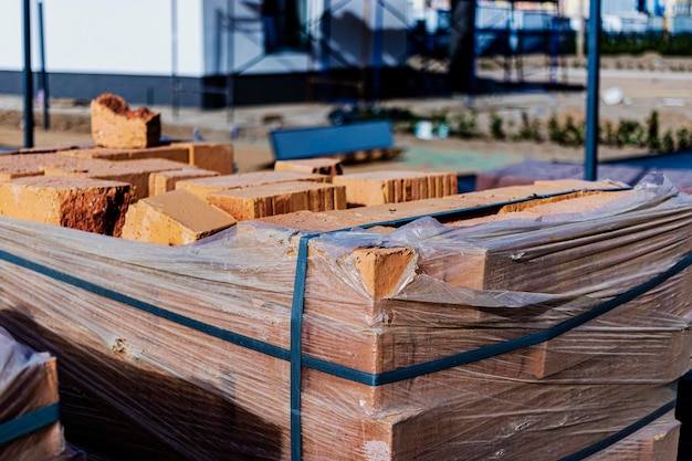 Briques en palettes sur un chantier de construction. Matériaux de construction. Brique rouge pour construire une maison.