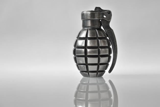 Un briquet comme une grenade à main sur fond gris avec un reflet.