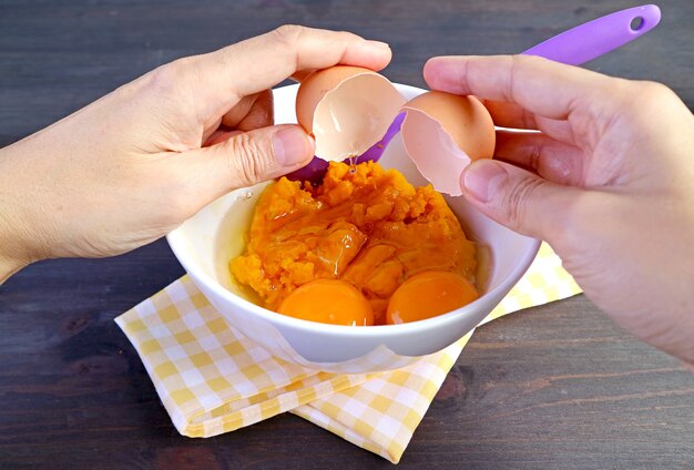 Briser à la main un œuf cru sur un arc de purée de citrouille pour le remplissage de tarte à la citrouille