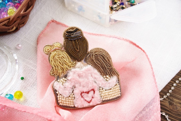 Broche maman et fille perles faites main sur table sur fond rose