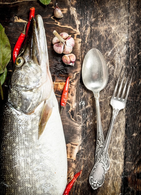 Brochet frais aux épices et vin blanc sur table en bois.