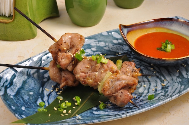 Brochette de filet de poulet asiatique savoureuse sur un bâton de bambou avec sauce