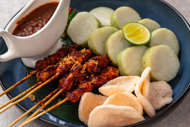 Brochette de satay de poulet avec viande grillée et gâteau de riz servi avec sauce aux arachides