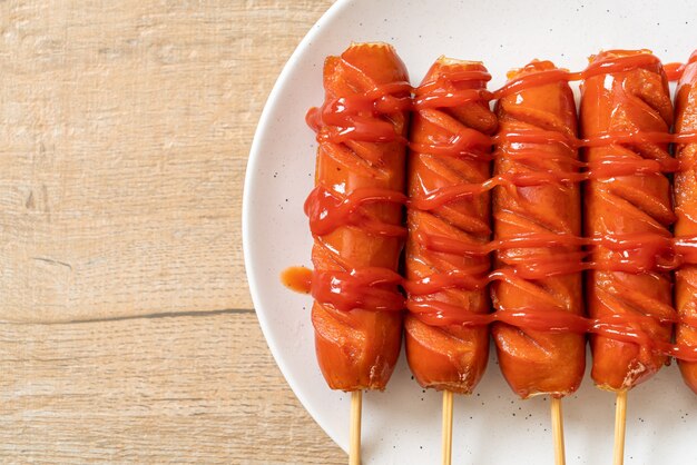 Brochette de saucisse frite avec du ketchup sur plaque blanche