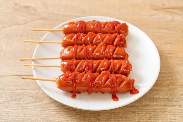 Brochette de saucisse frite avec du ketchup sur plaque blanche