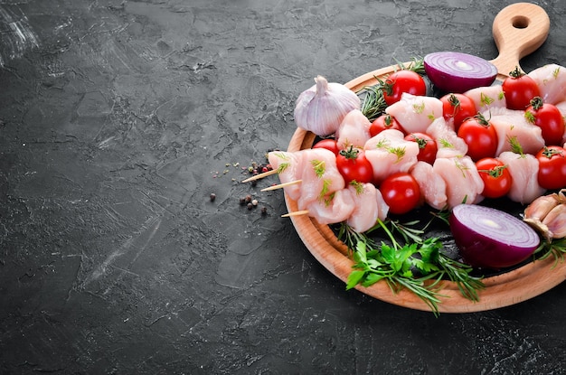 Brochette de shish de poulet cru avec tomates cerises Barbecue Sur fond de pierre noire Vue de dessus Espace de copie gratuit