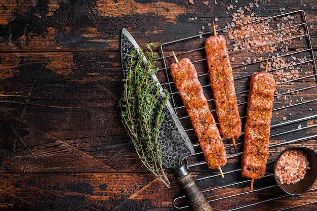 Brochette de shish Urfa crue non cuite sur un gril avec du sel rose Vue de dessus de fond en bois Espace de copie