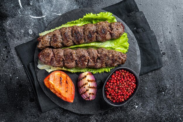 Brochette d'Urfa grillée avec salade de tomates et oignons Fond noir Vue de dessus