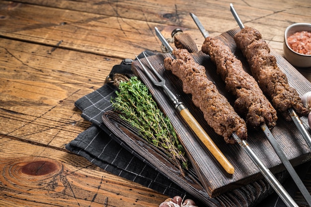 Brochettes d'Adana grillées au barbecue sur des brochettes de viande de bœuf d'agneau hachée. Fond en bois. Vue de dessus. Espace de copie.