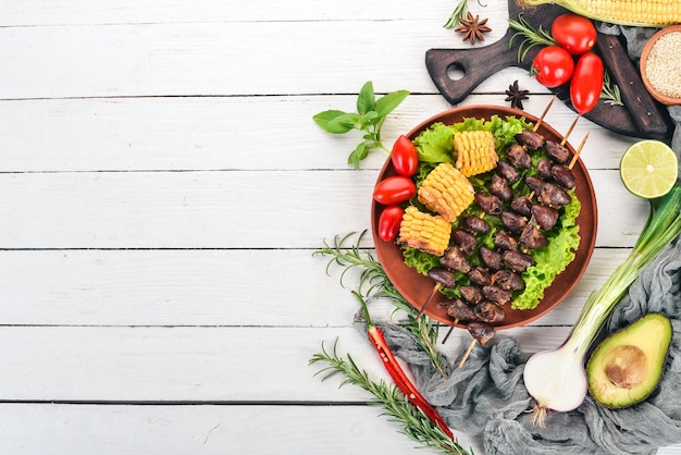 Brochettes de coeurs de poulet maïs et légumes frais Sur un fond en bois Vue de dessus Espace de copie gratuit