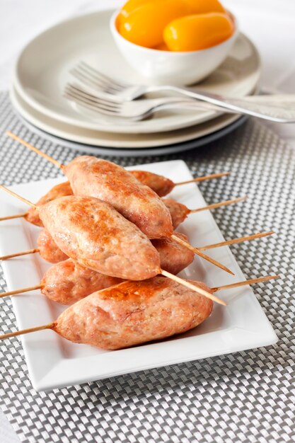 Brochettes de dinde hachées sur assiette carrée et tomates marinées jaunes à la surface