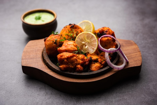 Brochettes indiennes de poulet tikka, marinées dans des épices et du yaourt et rôties au tandoor. servi avec chutney vert et oignon. mise au point sélective