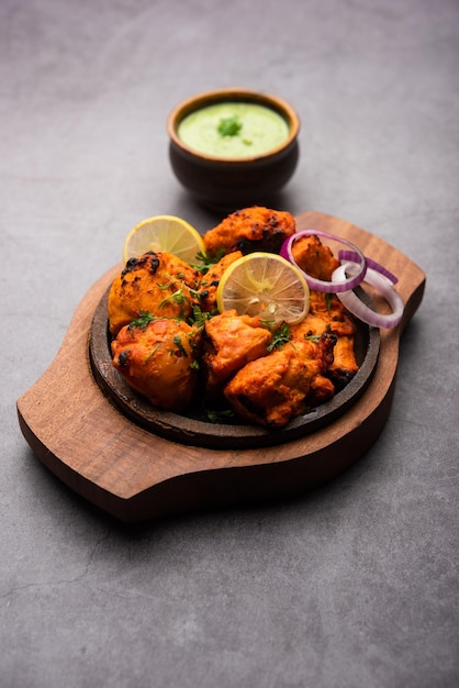 Brochettes indiennes de poulet tikka, marinées dans des épices et du yaourt et rôties au tandoor. servi avec chutney vert et oignon. mise au point sélective