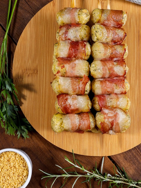 Brochettes de manioc enveloppées dans un médaillon de manioc au bacon