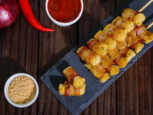 Brochettes de manioc enveloppées dans un médaillon de manioc au bacon