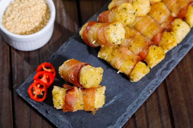 Brochettes de manioc enveloppées dans un médaillon de manioc au bacon