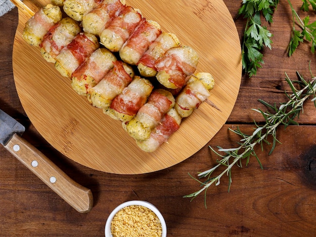 Brochettes de manioc enveloppées dans un médaillon de manioc au bacon