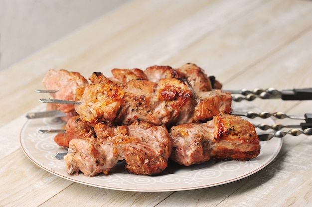 Brochettes de porc sur des brochettes dans une assiette sur un fond en bois