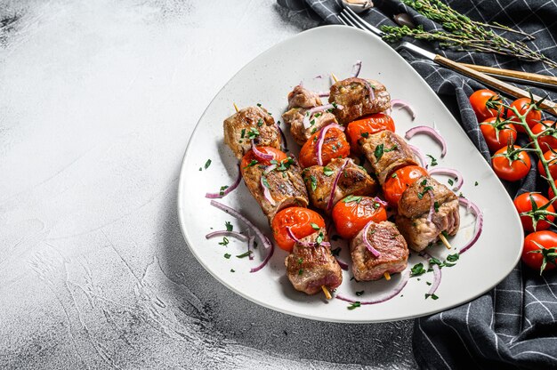 Brochettes de porc sur des brochettes de tomates