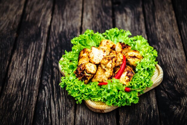 Brochettes de poulet au piment et laitue, sur fond de bois