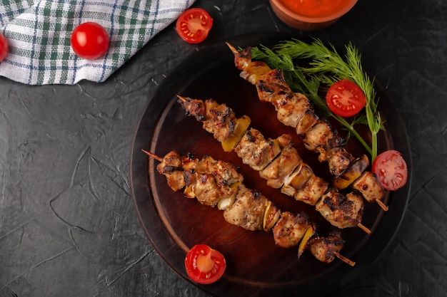 Brochettes de poulet aux pommes et légumes sur une surface noire. Mise au point sélective.