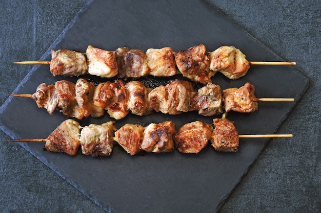 Brochettes rouges appétissantes sur une surface de pierre sombre. Vue de dessus.