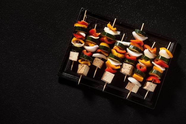 Brochettes végétaliennes de légumes et de tofu fumé dans une plaque à pâtisserie prête à cuire au four