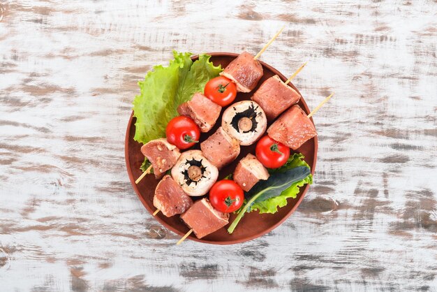 Brochettes de viande crue sur une assiette Sur un fond en bois Vue de dessus Espace de copie