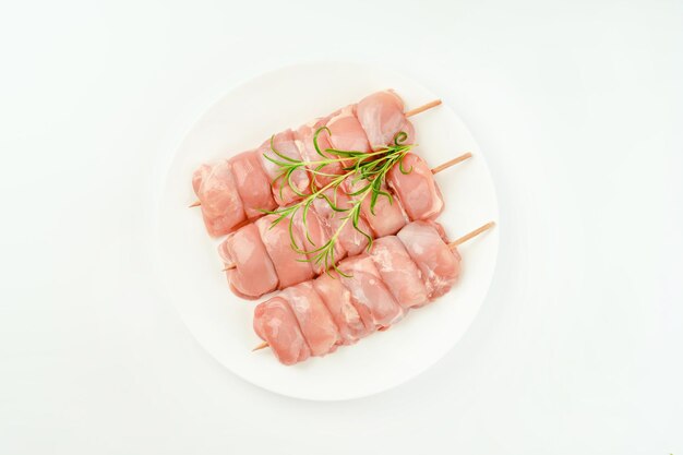 Photo des brochettes de viande de jambe de poulet crue sans peau pour un supermarché sur un fond blanc.